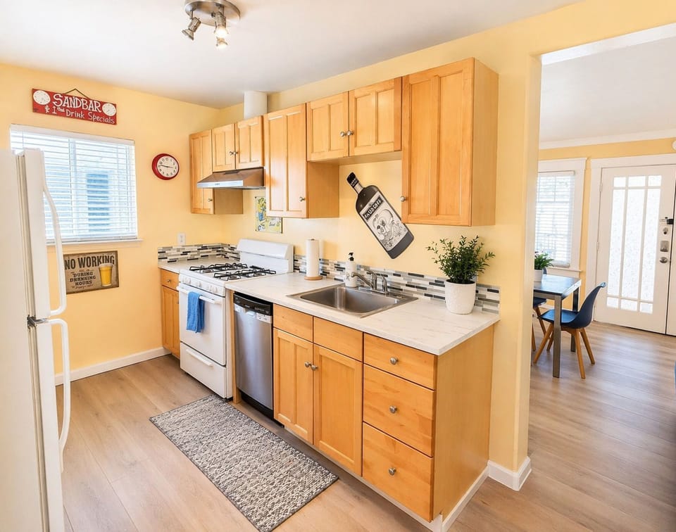Sunny galley kitchen with gas range, dishwasher, and cozy dining nook