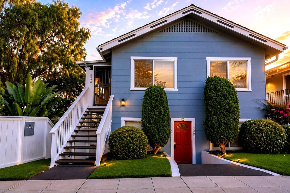 Charming blue home with red door, lush landscaping, and warm curb appeal