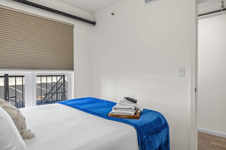 Alternate bedroom view showing the bed with a vivid blue throw, window and doorway.