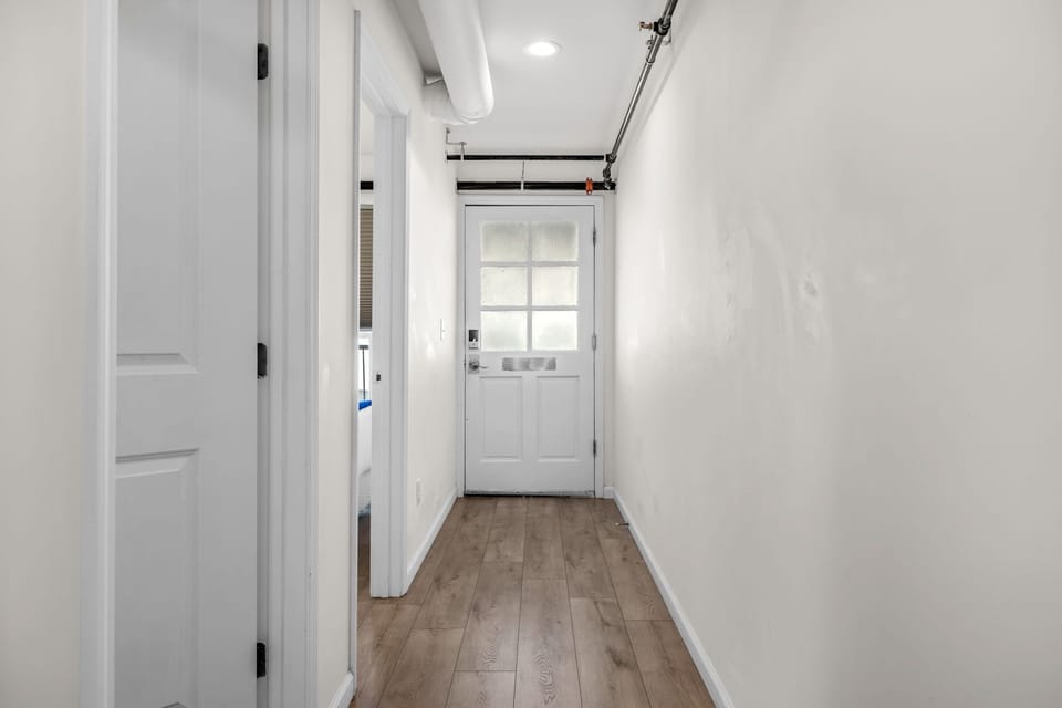 Interior hallway with wood-look flooring and a white entry door.