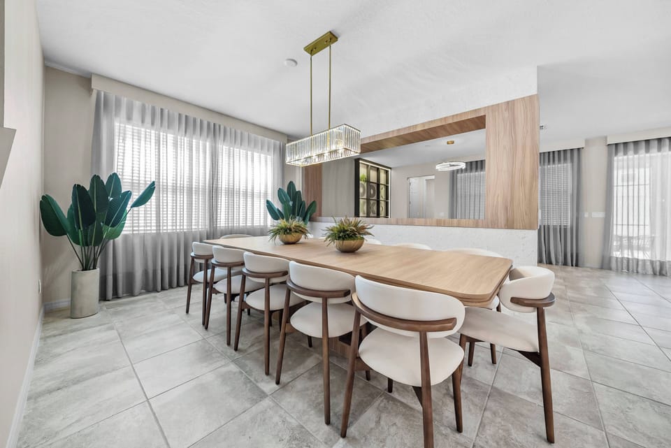 Enjoy a stylish dining area featuring a beautiful wooden table and modern upholstered chairs, perfect for gathering. Large windows with soft curtains let in natural light, enhanced by a chic pendant light above.