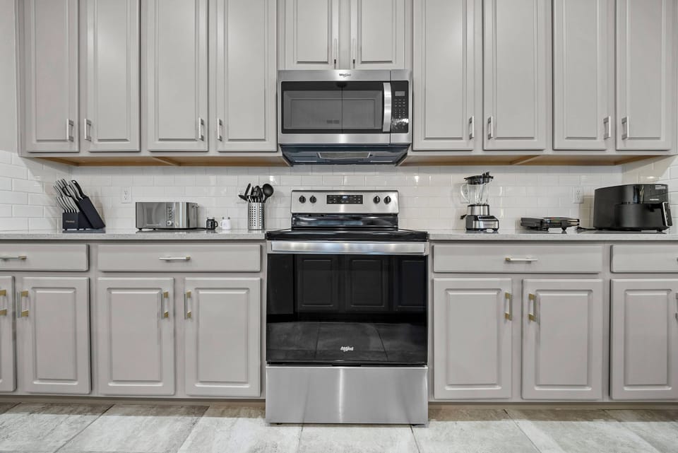This stylish kitchen boasts gray cabinetry and modern stainless-steel appliances, creating a polished atmosphere. The spacious countertop is perfect for preparing meals or enjoying your morning coffee in style.