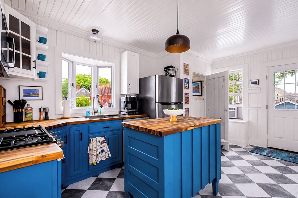 Bright designer kitchen with blue cabinetry, butcher-block island, and sunny windows