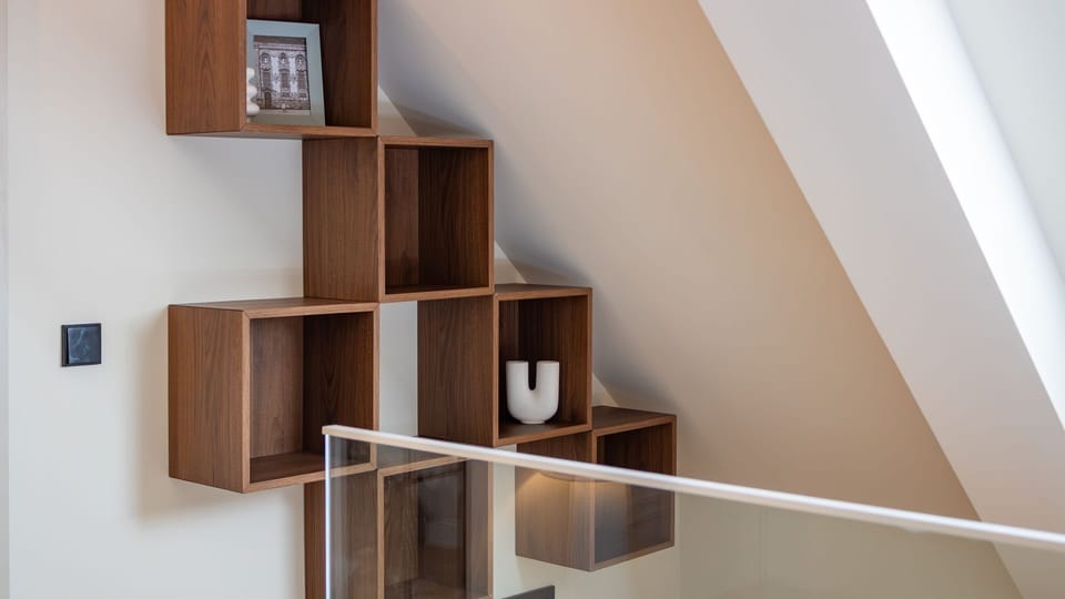 Discover unique, artfully arranged shelving that adds both style and storage, leading up a bright, airy space. The modern glass railing ensures safety while maintaining an open, elegant feel.