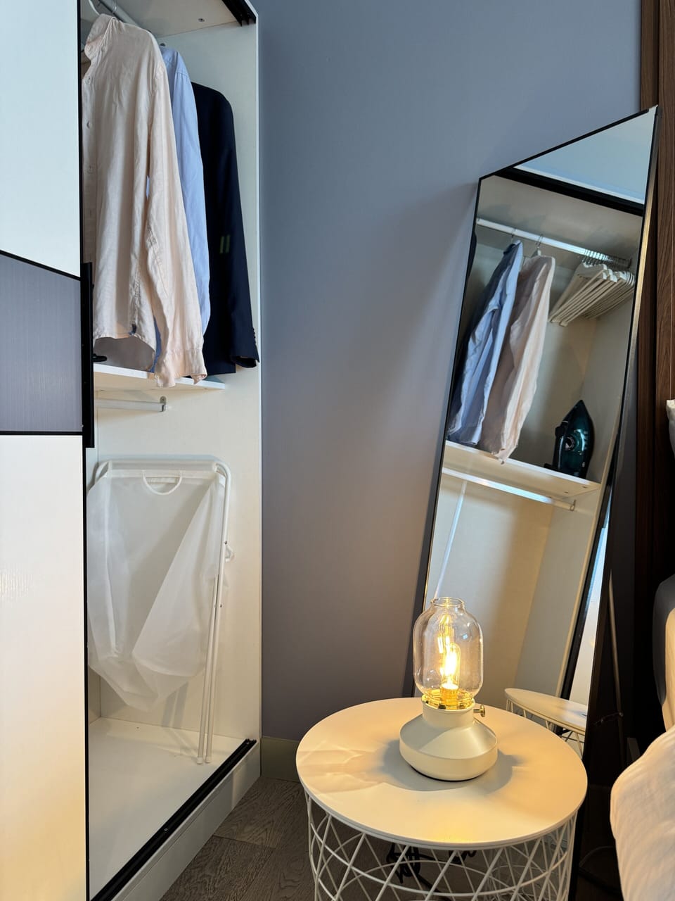 Organized wardrobe with full-length mirror, iron, and soft lamp glow
