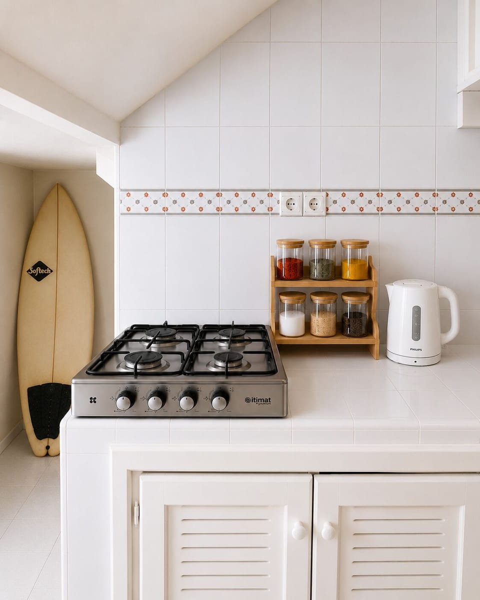 Bright beachy kitchen with gas cooktop, cooking condiments, electric kettle, and surf-inspired charm