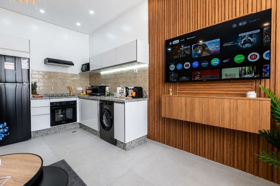 Modern kitchen with smart TV with IPTV & Netflix access, full appliances, and sleek wood accent wall