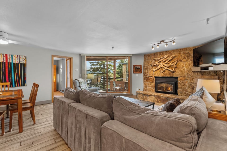 Sink into plush sofas by the stone fireplace, where warmth and mountain views create your perfect retreat after a day of adventure.