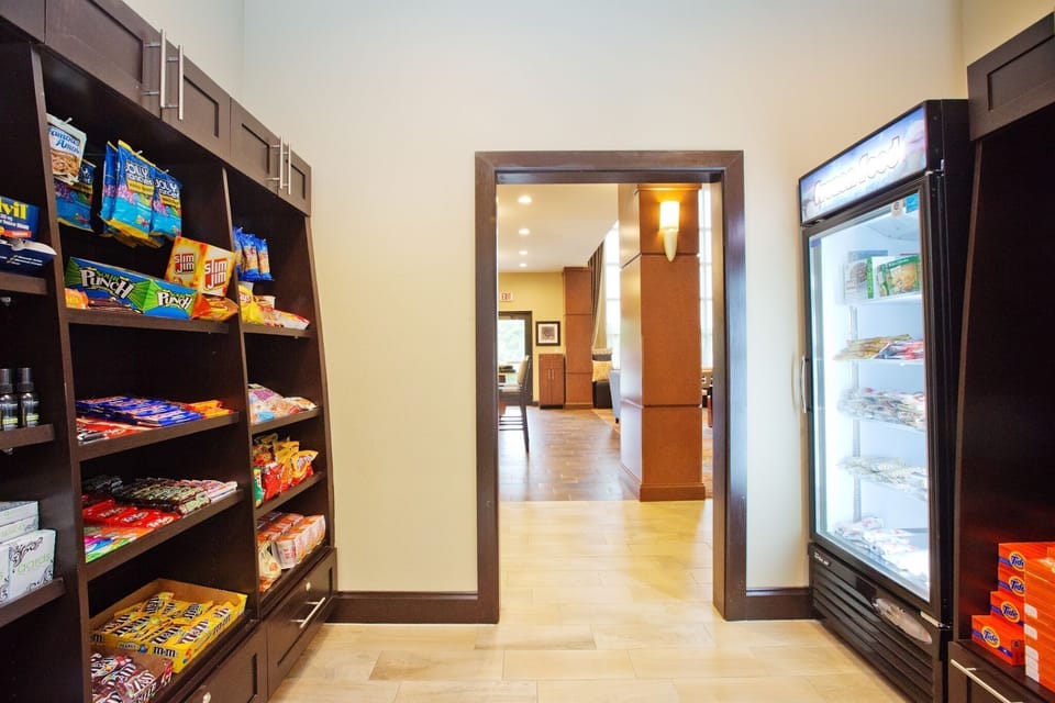 On-site pantry with snack shelves and a glass-front refrigerator stocked with packaged goods.