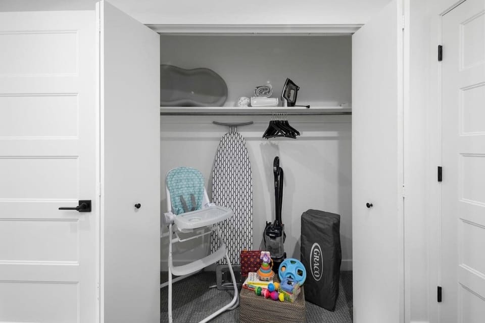 An ironing board and iron along with infant items including a high chair, changing pad, pack 'n play and corresponding sheets and blanket as well as toys and books are located in the bunk room closet. 