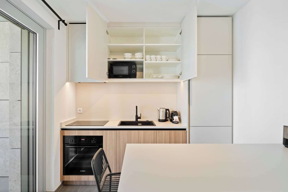 Sleek kitchen with microwave, oven, coffee maker, and practical storage for short or long stays.