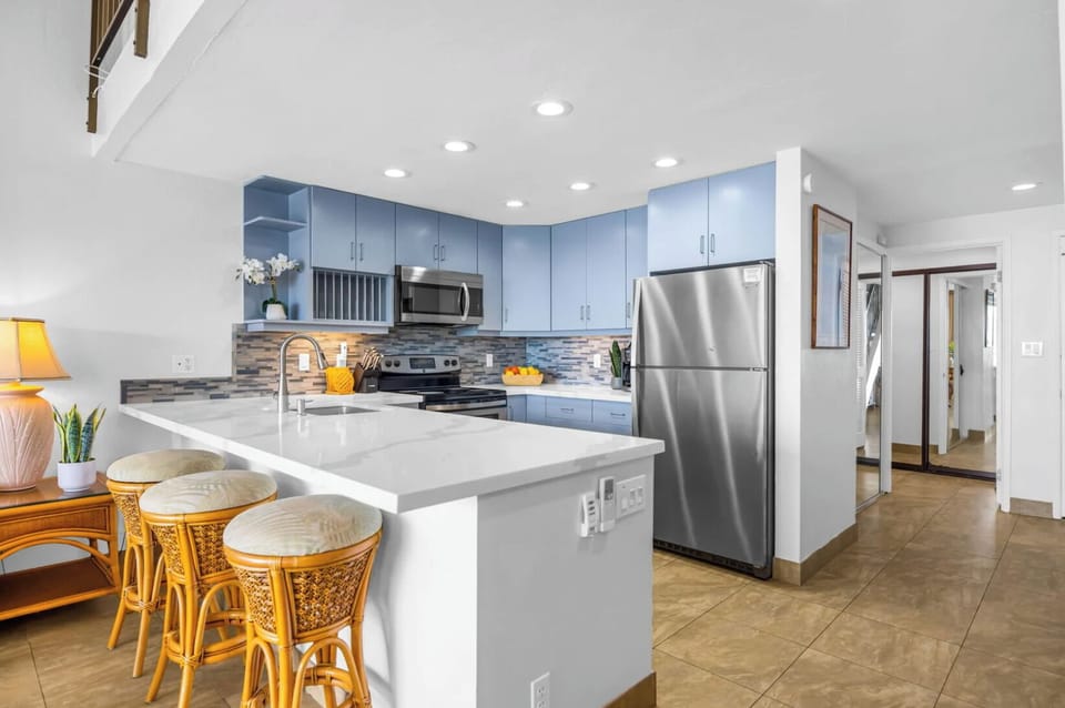 Unit 1 : Prepare meals in a modern kitchen featuring soft blue cabinetry, stainless-steel appliances, and a spacious island with bar seating for casual dining.
