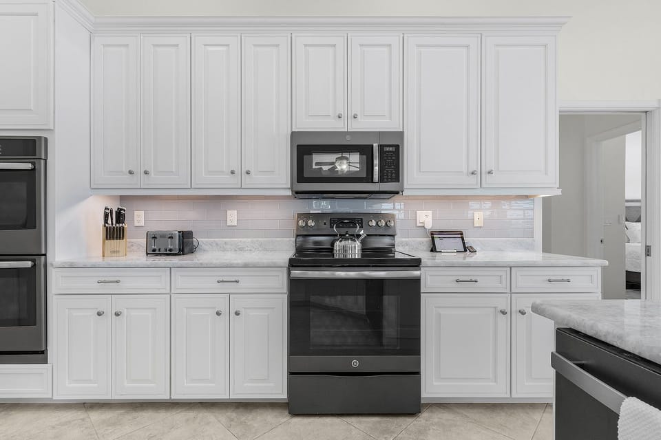 Bright and sophisticated, the kitchen offers ample white cabinetry and seamless integration for a premium cooking experience.
