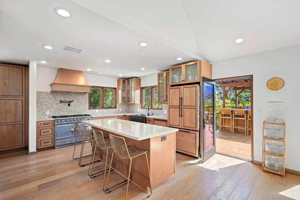 Chef-style kitchen with island seating, warm wood finishes, and direct access to the mountain-view deck.