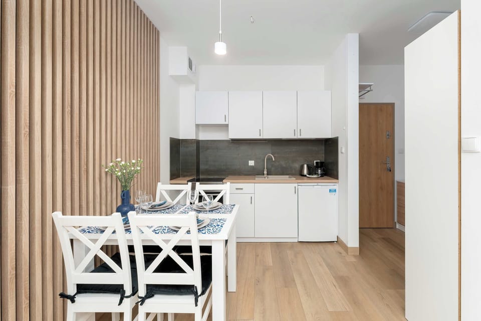 The layout shows the dining area positioned between a slatted wood accent wall and the kitchen counter. A bright entryway hallway is visible in the background.