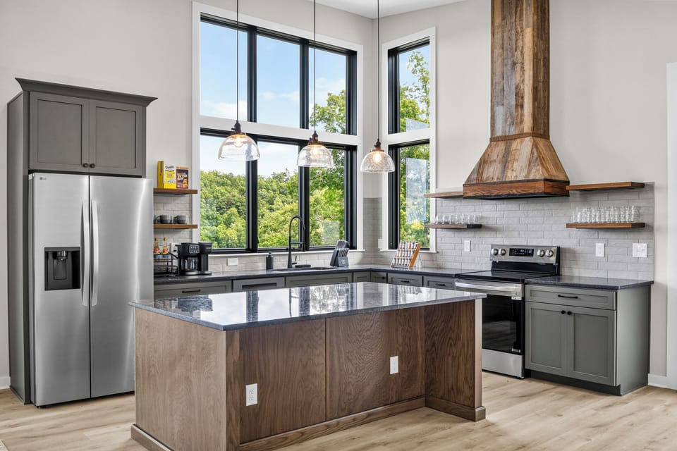 Bright designer kitchen with large island, tall windows, and scenic views