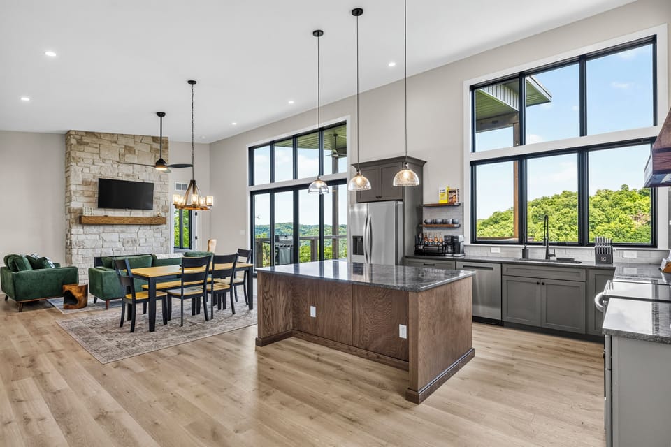 Bright open-concept great room with stone fireplace and scenic views