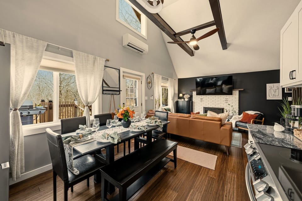 Bright vaulted great room with fireplace, deck access, and stylish dining area