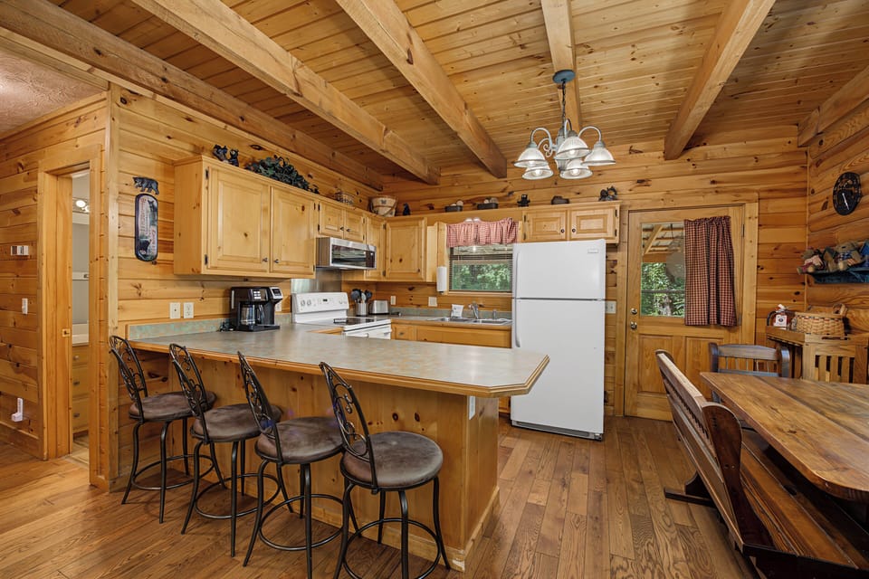 Gather around the rustic wooden island with comfortable seating, where you'll find everything you need to prepare delicious meals in this fully equipped cabin kitchen with modern appliances.