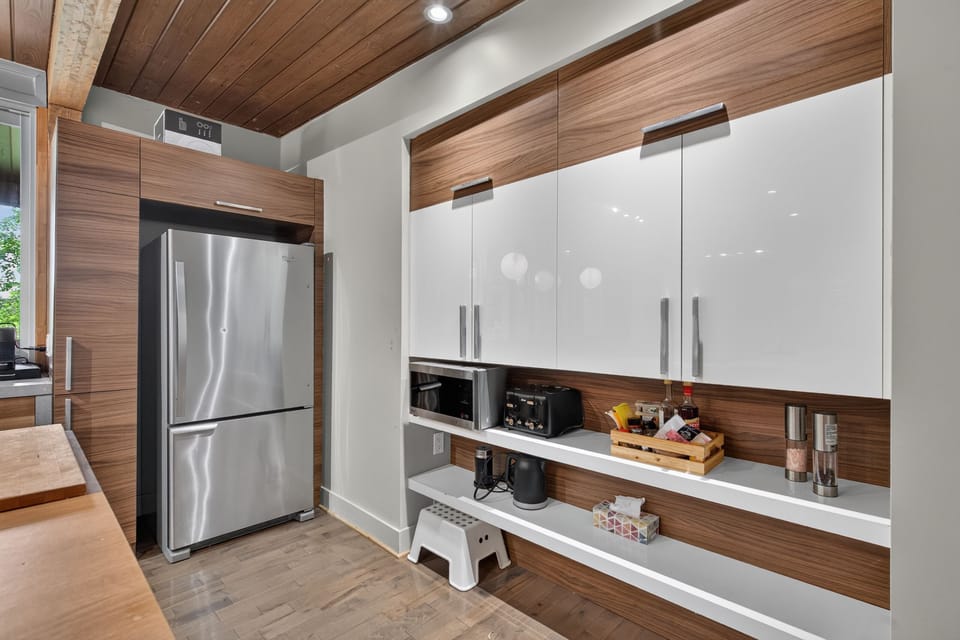 Modern kitchen with sleek cabinetry, stainless fridge, and warm wood accents