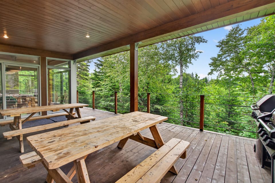 Covered forest-view deck with picnic tables and grill for outdoor dining