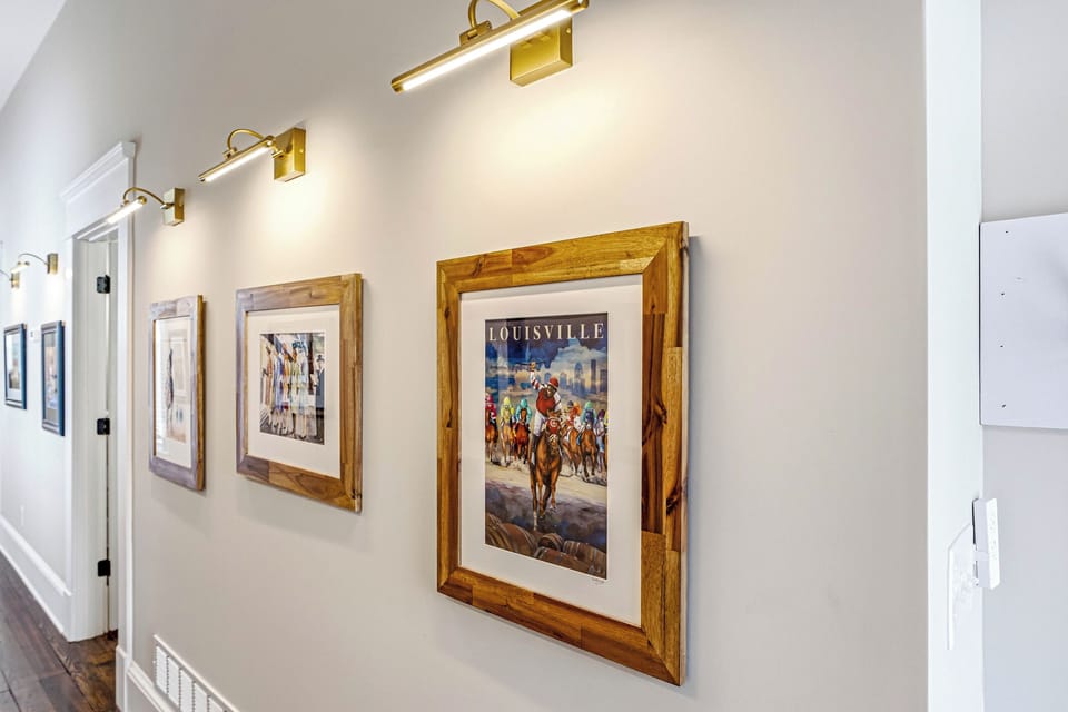 The gallery-style hallway sets the tone, lined with framed horse racing art under warm picture lights.
