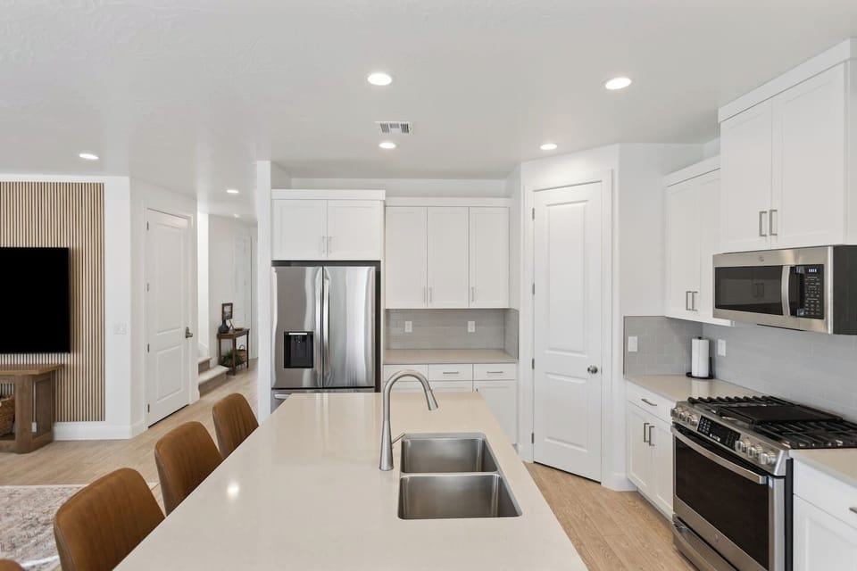 Fully stocked kitchen with stainless steel appliances and thick solid-surface countertops opening to the great room
