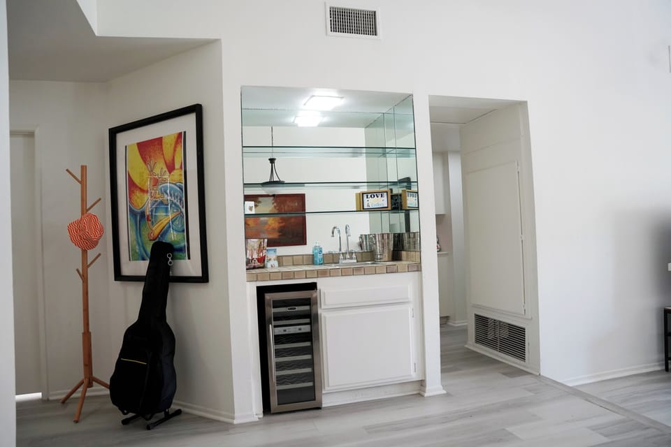 Ideal for evening relaxation, this elegant wet bar area boasts a built-in wine and beverage refrigerator, a convenient prep sink, and a mirrored display shelf to hold your favorite glassware.