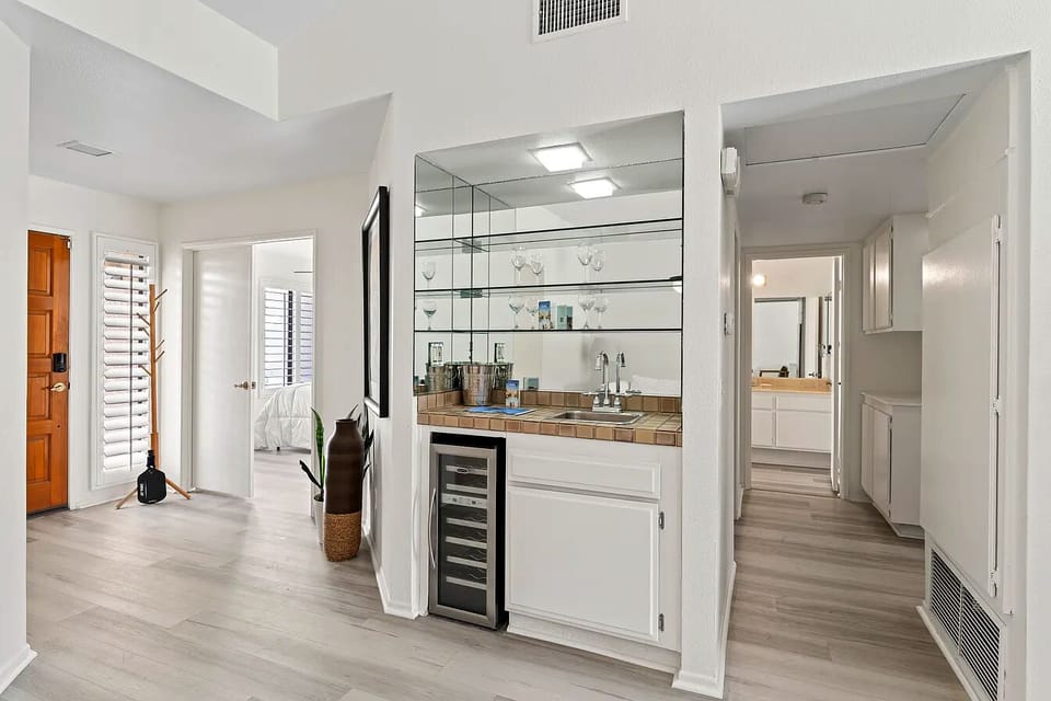Enjoy the convenience of a dedicated wet bar area, complete with a built-in wine cooler, pristine glassware, and a mirrored backdrop—perfect for mixing evening drinks or storing refreshments.