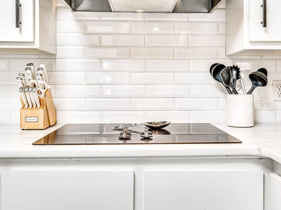 Clean, updated kitchen cooktop in a Brookhaven Norman OK Airbnb — bright backsplash and easy meal prep space.