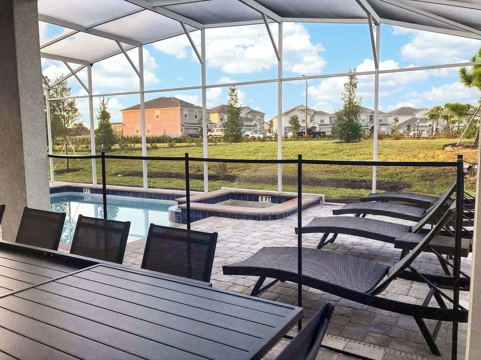 Patio seating and lounge chairs positioned next to the screened pool.