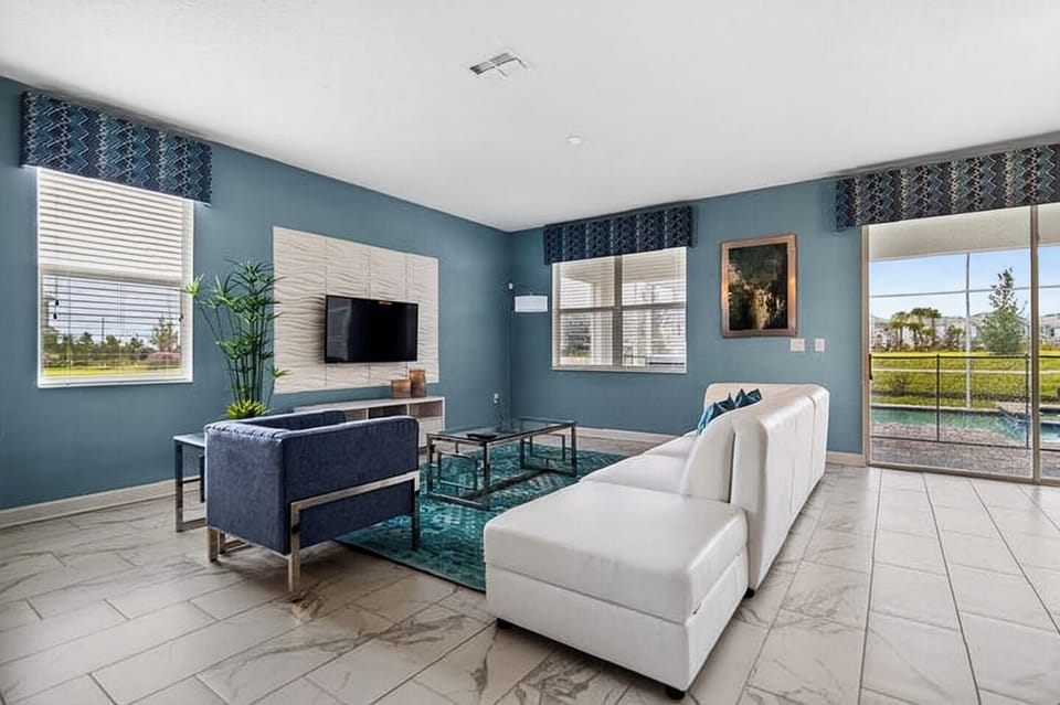 Spacious living room featuring modern white and blue sofas and a large flat-screen TV.