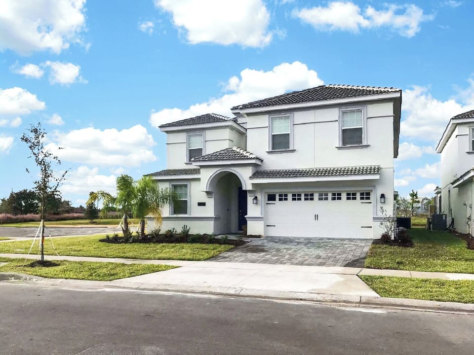 Front exterior view of the two-story contemporary white house with a paved driveway.