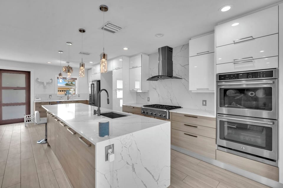 Polished kitchen with a waterfall island, high-end appliances, and a bright view toward the outdoor dining area.