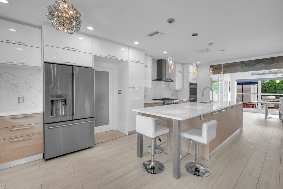 Polished kitchen with a waterfall island, high-end appliances, and a bright view toward the outdoor dining area.