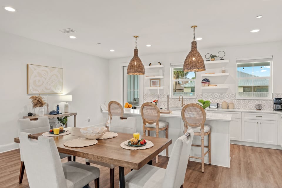 Spacious dining area and coastal kitchen with island seating, woven pendants, and easy backyard access.