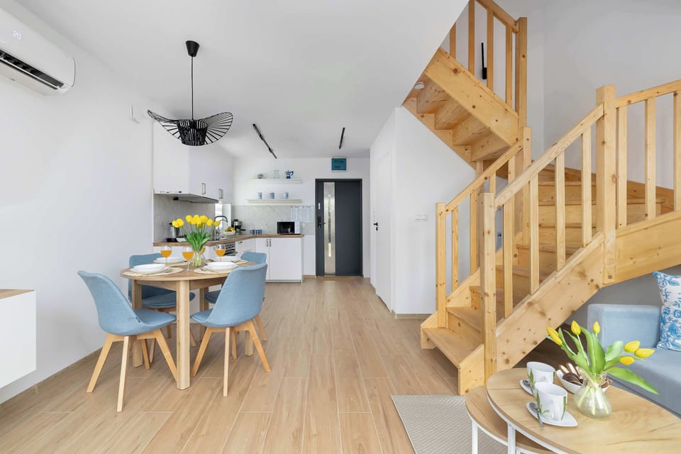 A compact dining corner with a wooden table, blue chairs, and a sleek kitchenette counter visible in the background. The design maximizes space without sacrificing comfort or style.