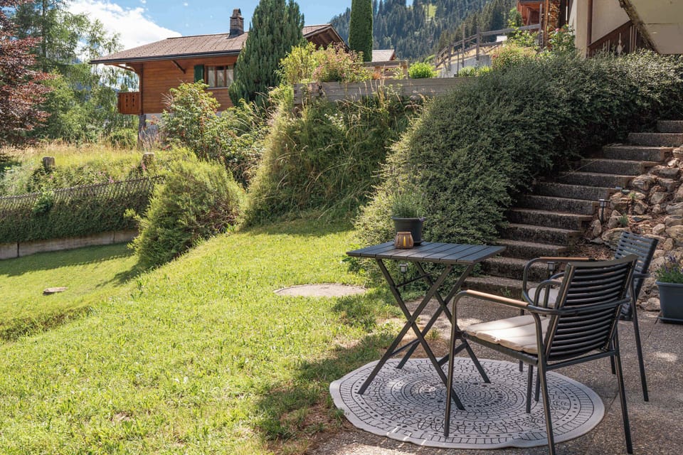 Peaceful private garden with seating area surrounded by alpine scenery.

