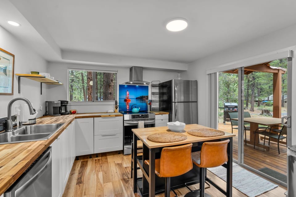 Cook up your favorite meals in this modern, fully equipped kitchen with butcher block counters, stainless steel appliances, and forest views through the windows. Step outside to your private deck for alfresco dining.
