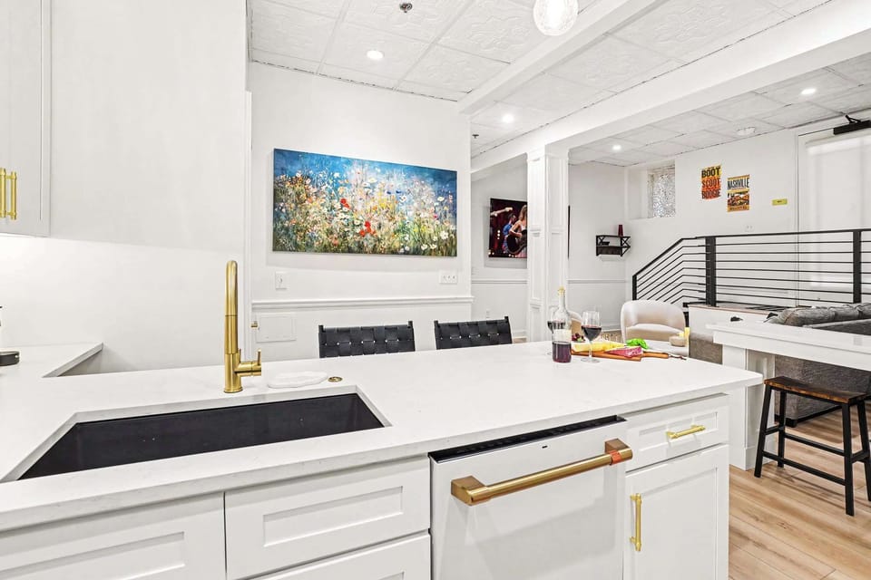 This white kitchen shines with brass and gold accents, high-end appliances, and an oversized island perfect for entertaining, all under a stunning pressed-tin ceiling for character.