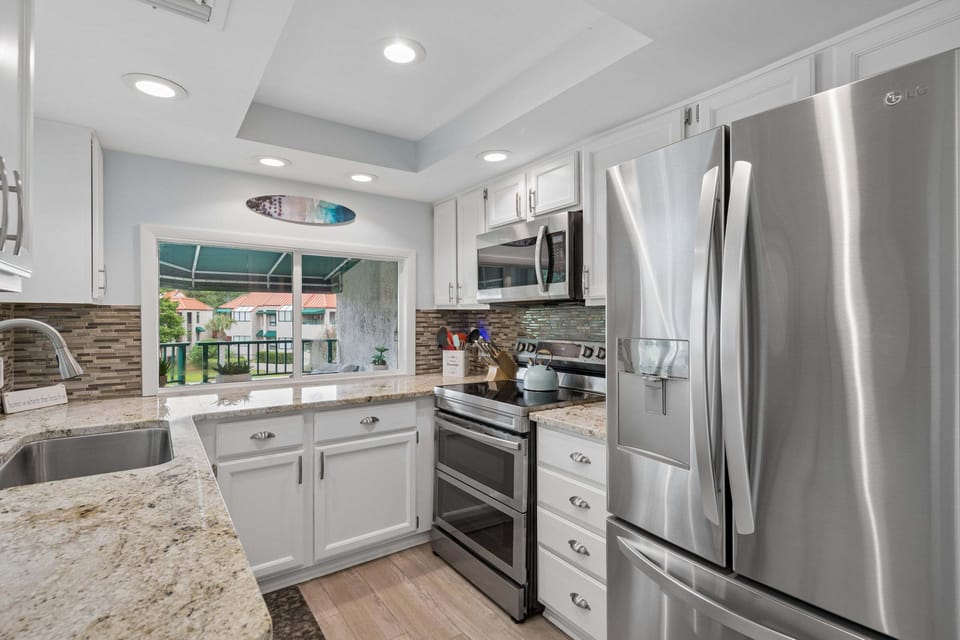 Stainless steel appliances, granite countertops, a tile backsplash, and a Keurig ready for slow mornings