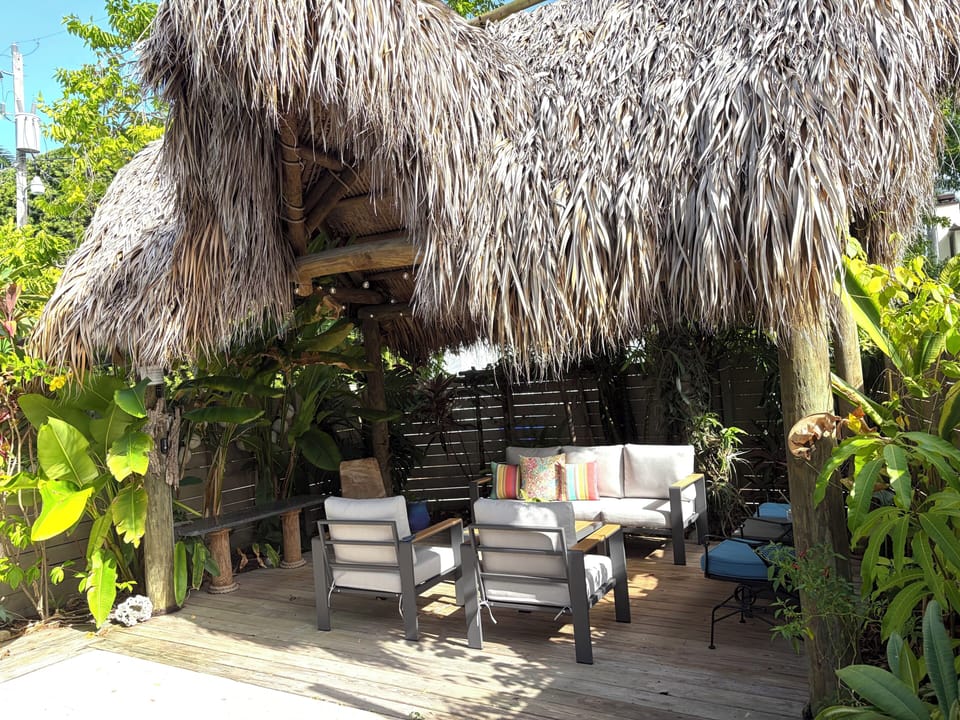 Tropical tiki lounge with shaded seating and lush garden privacy