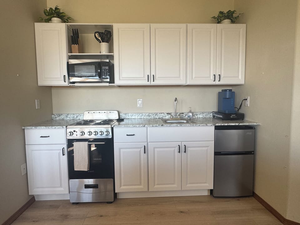 Kitchen includes plates, bowls, silverware, coffee cups, pots, pans, cutting boa