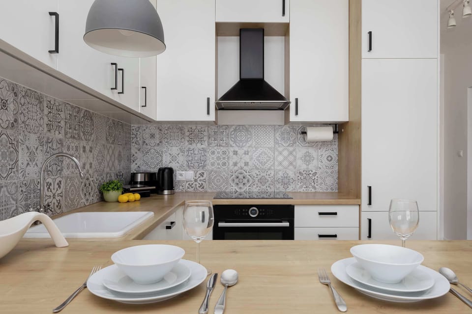 Fully equipped open-plan kitchenette featuring modern appliances and a stylish tiled backsplash.