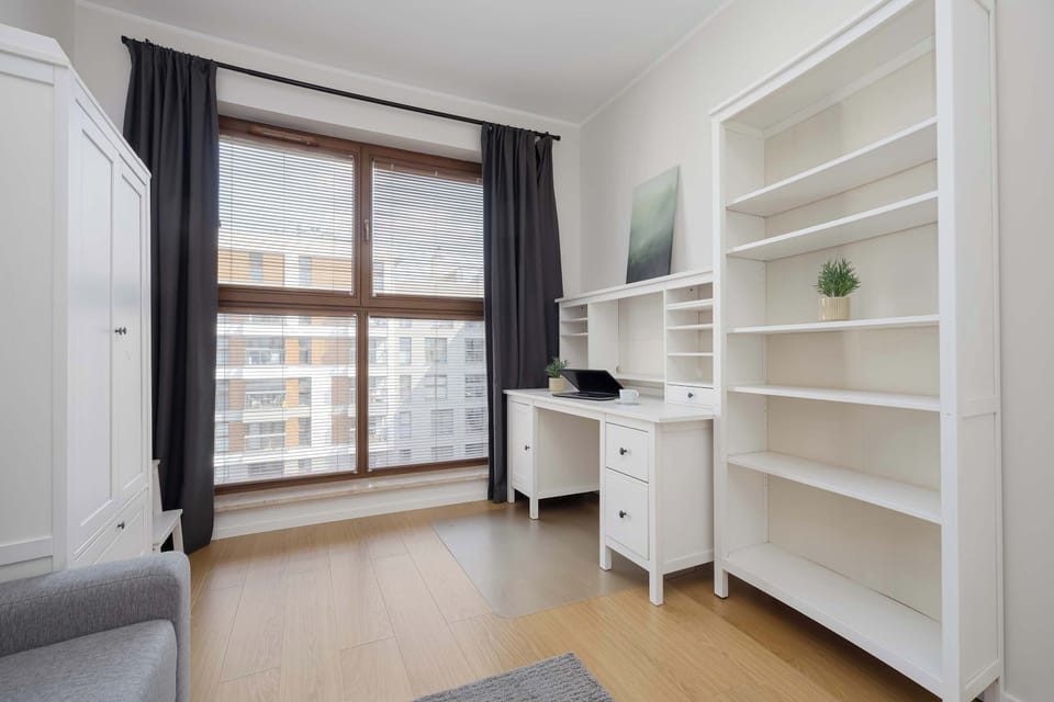 Bright second bedroom with a sofa bed, built-in wardrobe, and a practical workspace.