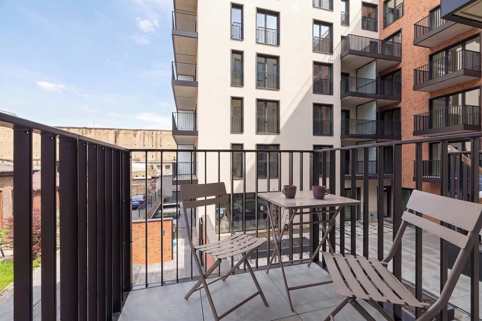 Private balcony with outdoor seating overlooking the modern residential complex.
