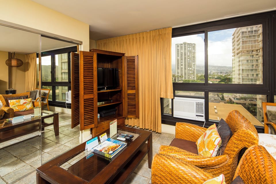 Relax in your island-style living space with comfortable woven seating and entertainment center. Panoramic windows frame the city skyline while cool air conditioning keeps you refreshed. Your private urban retreat awaits.
