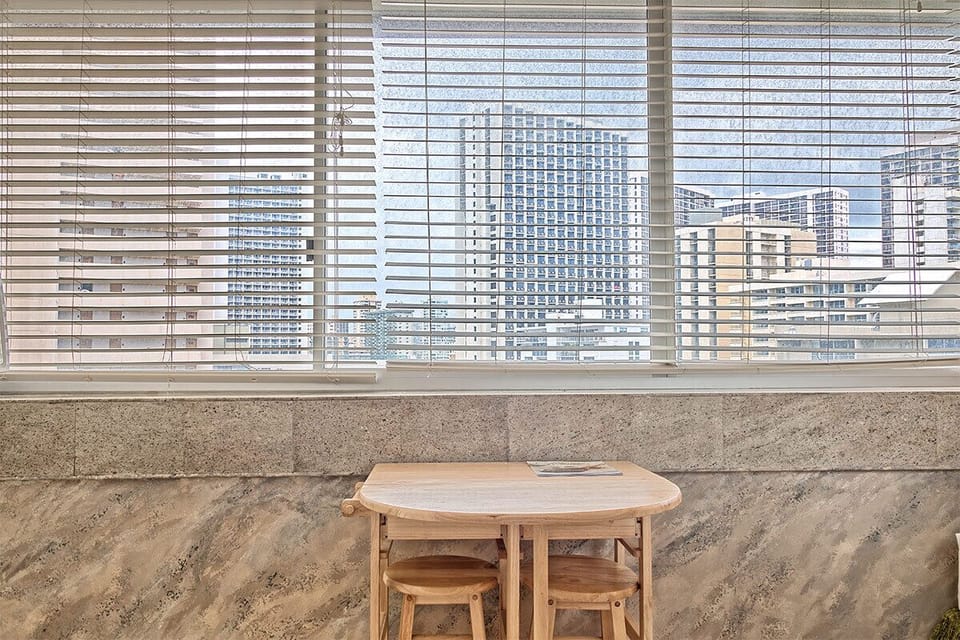 Light-filled seating nook with city skyline views beyond the window blinds. Perfect for your morning coffee or planning your day.