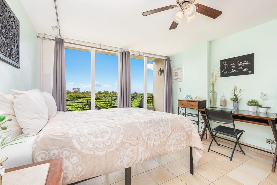 Drift off to sleep in your airy bedroom with ceiling fan and sweeping views of lush green landscapes through expansive glass doors.
