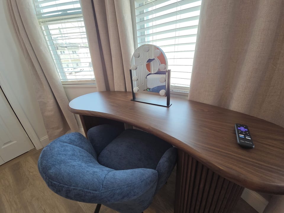 Bright vanity nook with cushioned chair and stylish curved wood desk